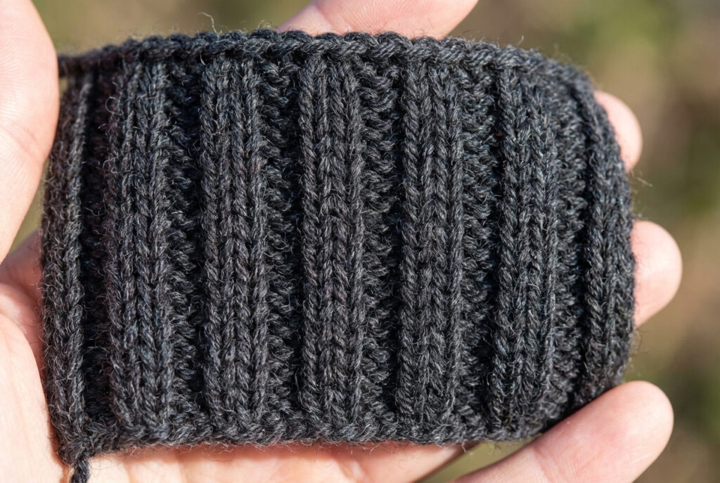 Close-up of a ribbed knitting swatch showing the difference between knit V-stitches and purl bump stitches