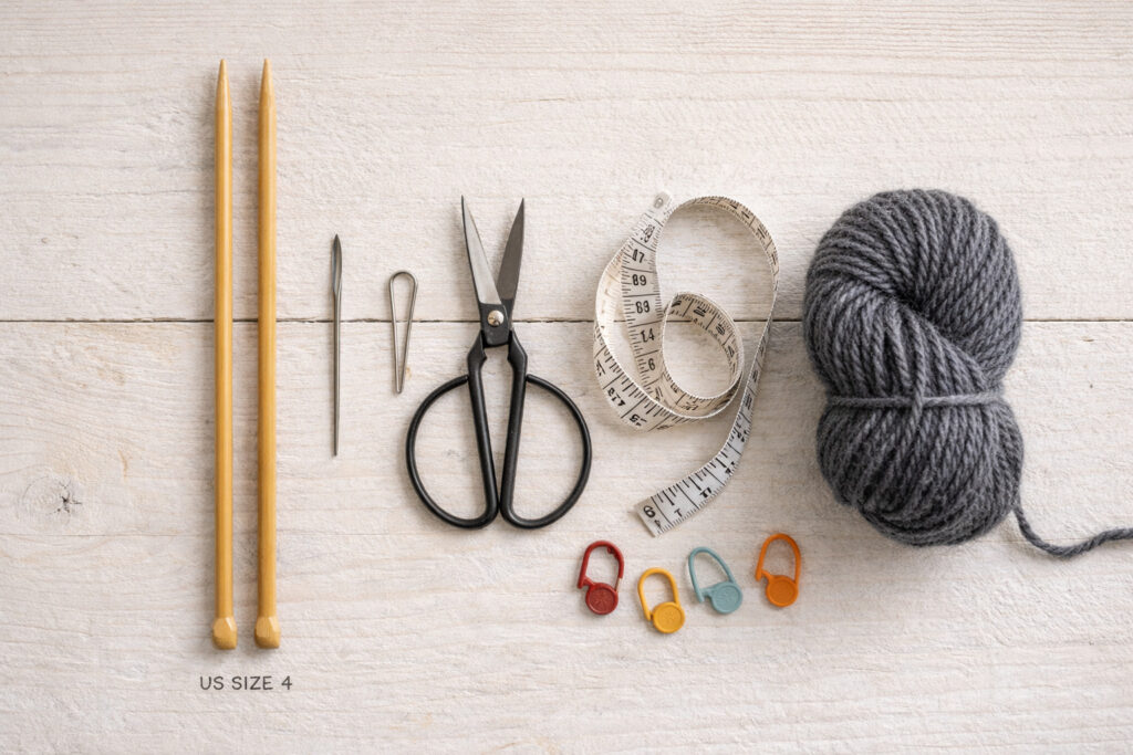 Knitting tools for making a tie including bamboo needles, tapestry needle, scissors, measuring tape, and stitch markers