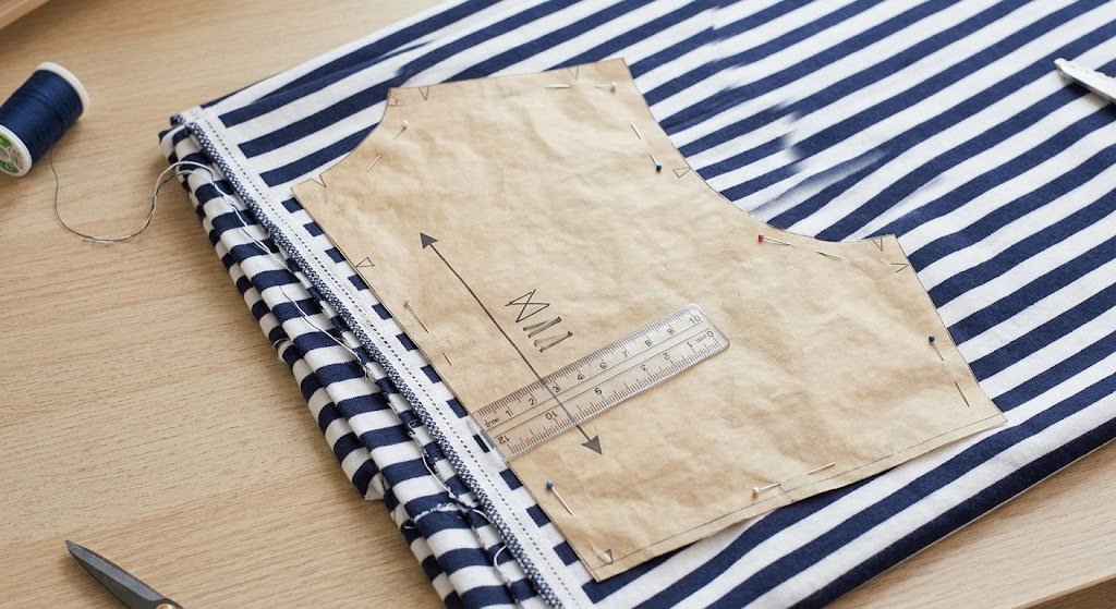 Shirt pattern piece aligned with the fabric grainline parallel to the selvage on striped cotton