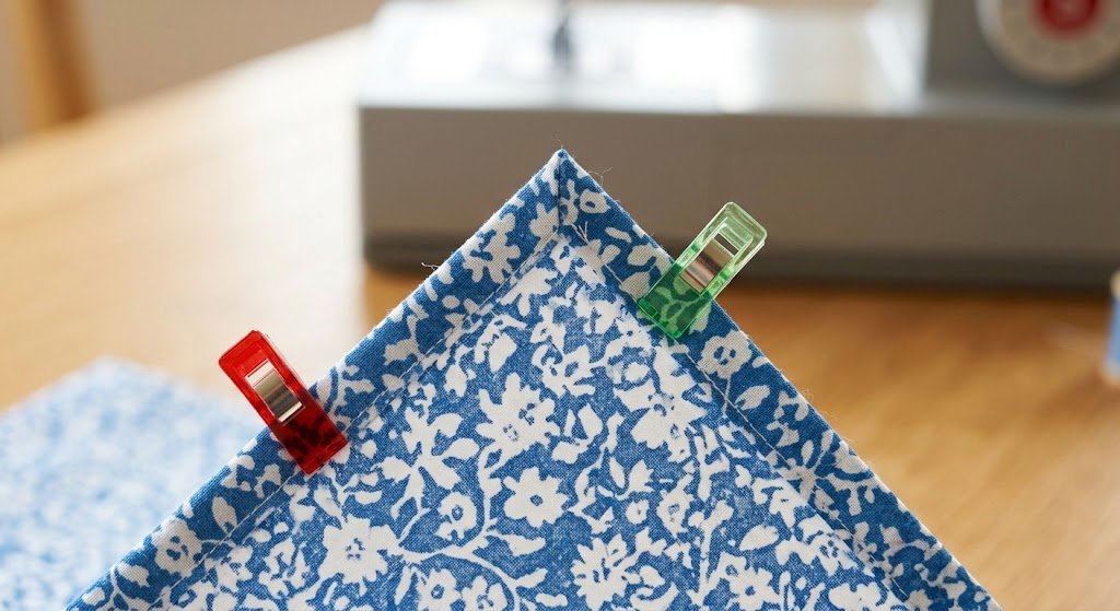 Double-fold bandana hem secured with fabric clips, showing a neat folded corner